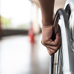 Close-up of a disabled man's hand, holding the wheel of his wheelchair.
