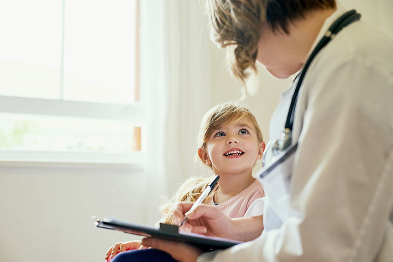 Female doctor in consultation with a smiling little girl.