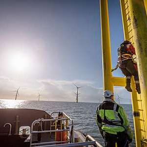 Engineers climbing wind turbine at offshore wind farm
