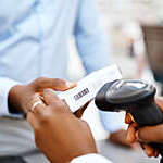 Close shot of pharmacist’s hands scanning a box of medication held by a customer.