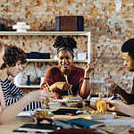 Young people of different backgrounds and cultures enjoy a friendly chat over lunch.