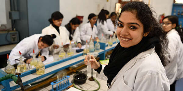 Girls in white lab coats attend a chemistry class in a laboratory at Rajas College, University of Delhi, India.
